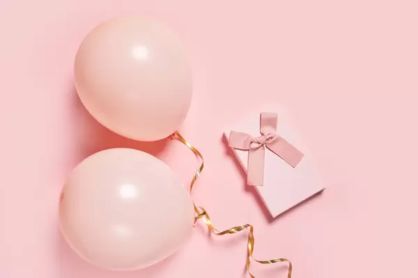 Balloons and present box on pink background