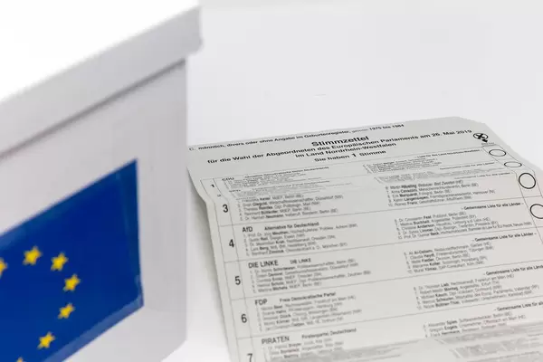Ballot paper of the postal voting documents for the European election 2019, with a list of participating German parties, next to an EU ballot box