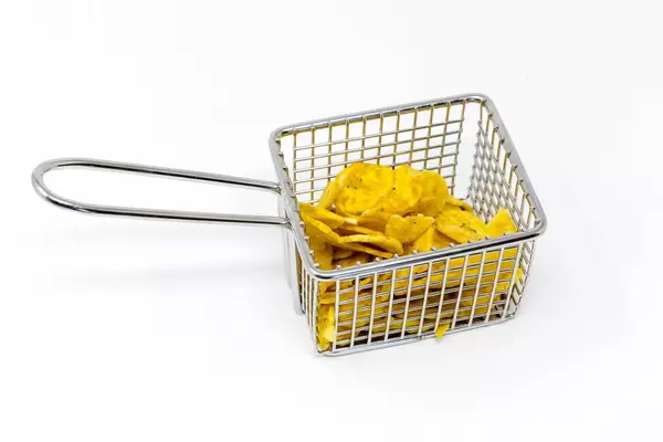 Bananenchips in einem Fritösenkorb auf weißem Hintergrund