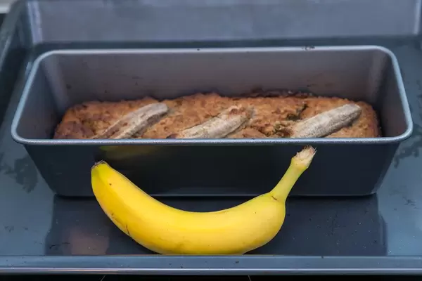 Bananenkuchen gebacken in einer Backform hinter einer reifen Banane platziert