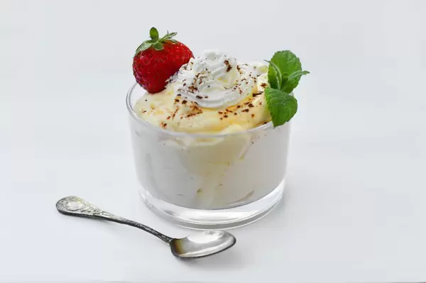 Bananenmousse mit einer Erdbeere, Sahne und Pfefferminzblättern in einem Schälchen aus Glas