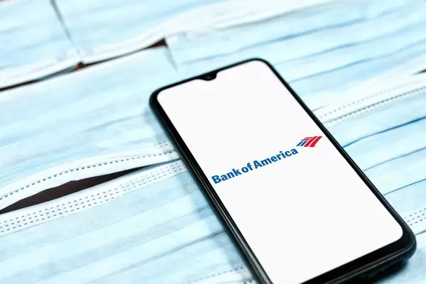 Bank of America logo on smartphone screen over the face masks. Coronavirus crisis changing global business rules