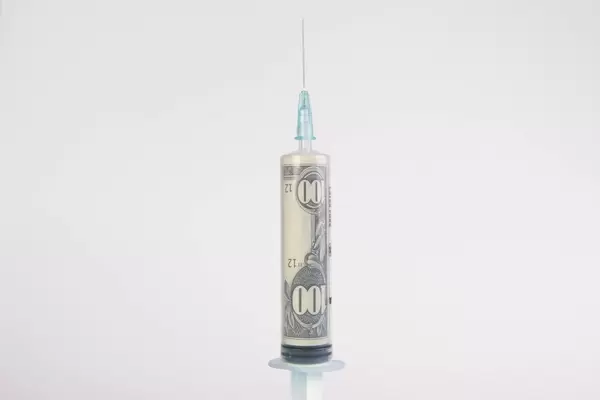 Banknote of $100 inside a syringe for injections