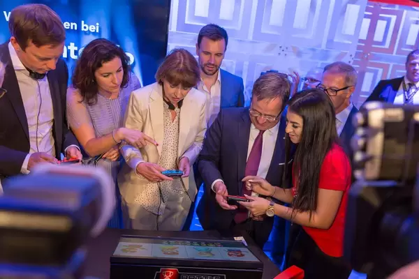 Bär, Reker und Laschet im Begriff Super Mario Party zu spielen. Hostess erklärt die Bedienung