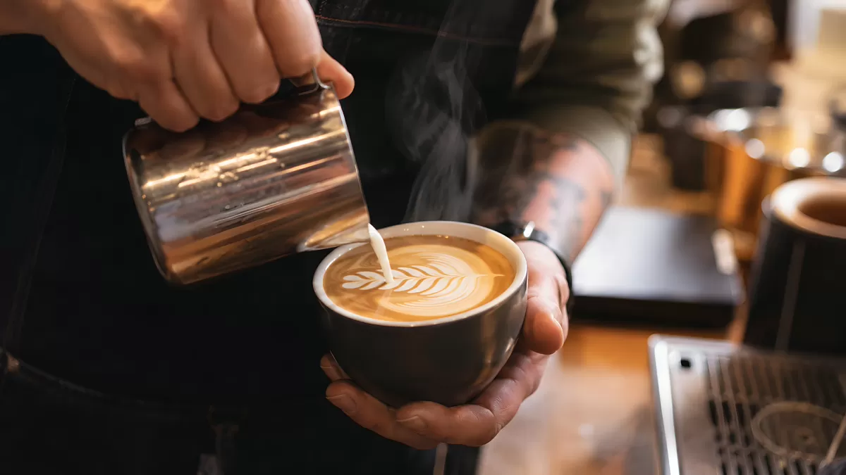 Barista gießt Milchschaum-Latte-Art in Kaffeetasse