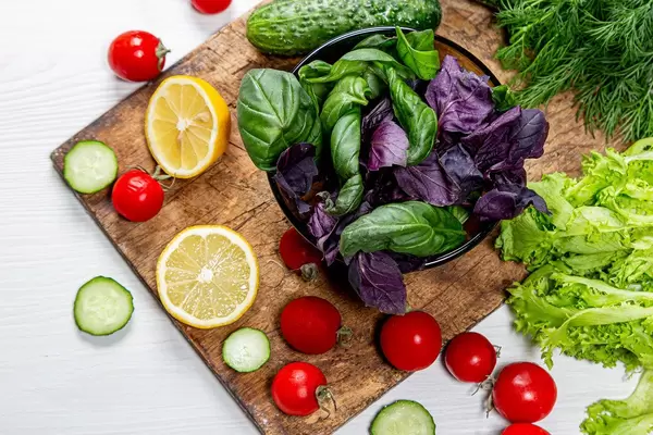 Basil, tomatoes, cucumber and lemon slices with fresh herbs on an old wooden Board