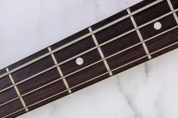 Bass Guitar Neck with Strings above marble background (Flip 2019)