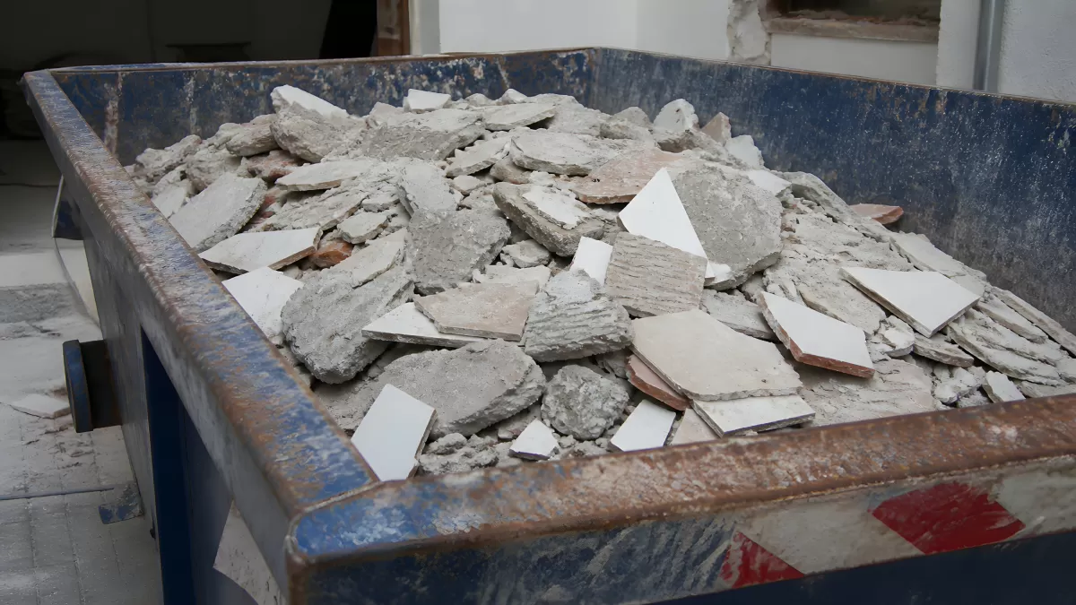 Bauschutt mit Fliesenresten in blauem Containerbehälter