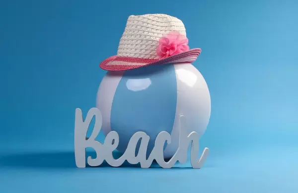 Beach ball with sun hat and beach text on blue background