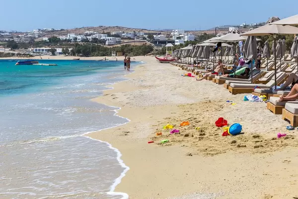 Beach sand toys by the seashore and tourists sunbathing at Kalafati beach, Mykonos, Greece