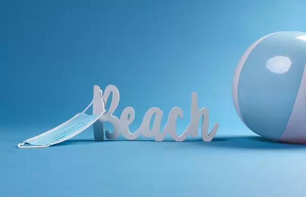 Beach text with beach ball and medical face mask on blue background