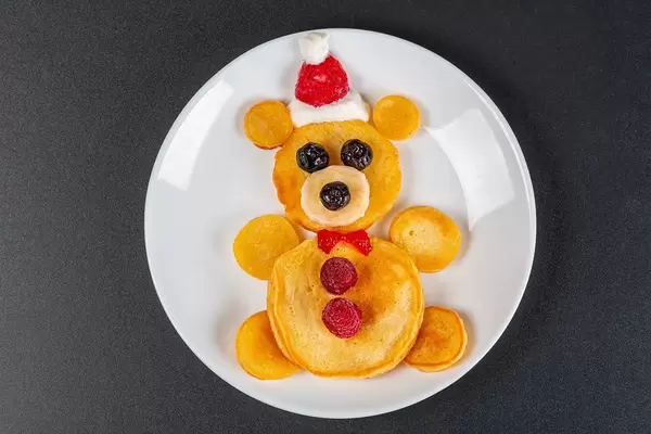 Bear pancakes with berries for kids breakfast on black background, top view