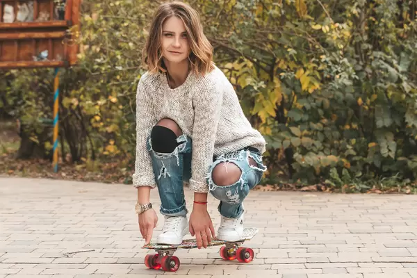 Beautiful and fashion young woman posing with a skateboard