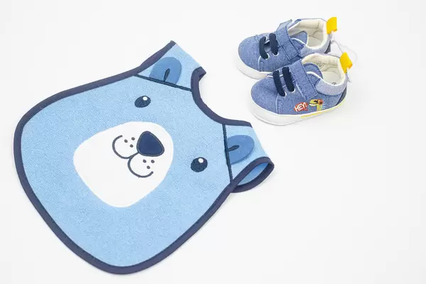 Beautiful Baby Bib with small baby shoes above white background with copy space