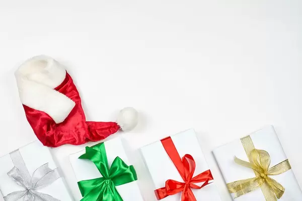 Beautiful Christmas gifts and Santa cap on white background