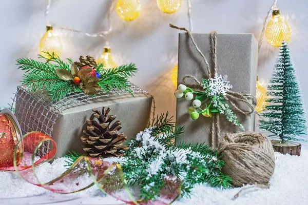 Beautiful decorated gift boxes and New Year's décor with a Christmas tree, snow and luminous garland.