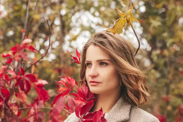 Beautiful girl with red leaves outdoors