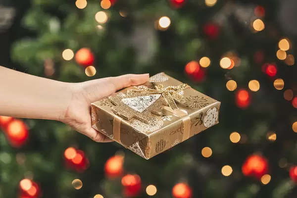 Beautiful new year background with a golden gift in a woman's hand