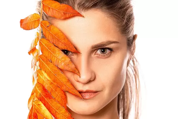 Beautiful portrait of young woman with autumn leaf
