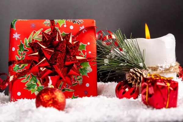 Beautiful red gift with burning candle and snow