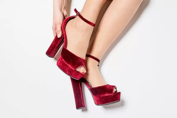 Beautiful young woman choosing and buying shoes in boutique