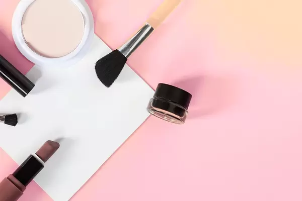 Beauty concept. Woman cosmetics accessories and white paper sheet on bright background