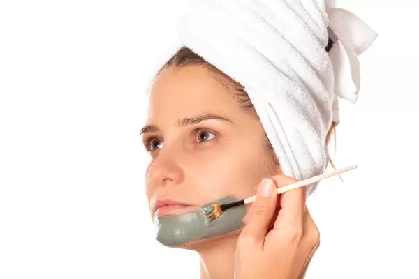 Beauty procedures skin care concept, woman no makeup applying facial gray clay mask to her face