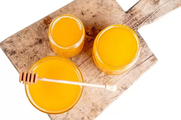 Bee honey in jars and bowl on old kitchen board, top view