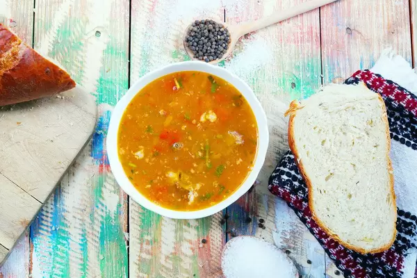 Beef soup served with white bread, salt and pepper. Wooden vintage table (Flip 2019)
