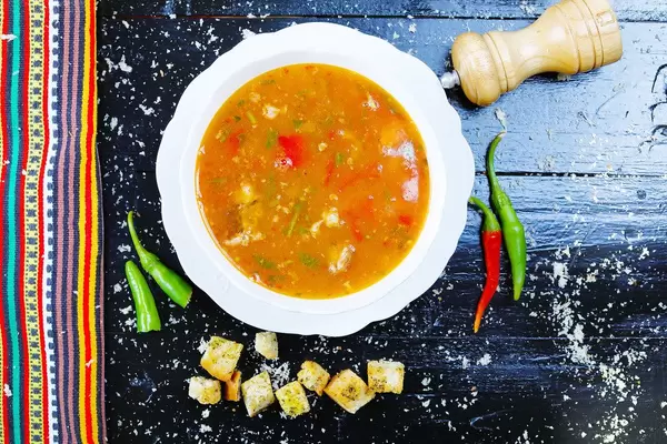 Beef soup with croutons and fresh pepper, black wooden background (Flip 2019)