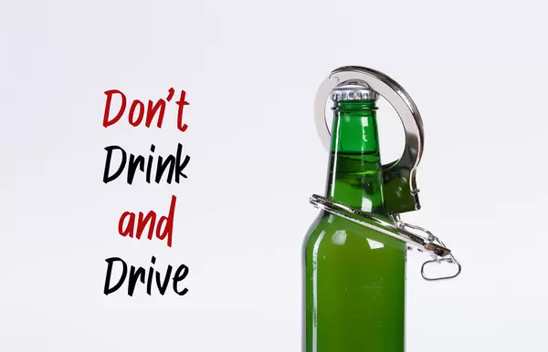 Beer bottle chained with handcuffs and Don't drink and drive text