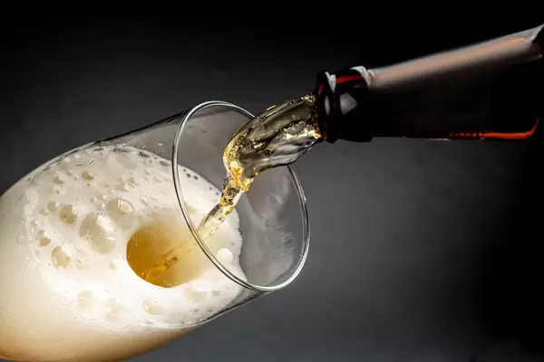 Beer pouring into a glass with foam on a dark background