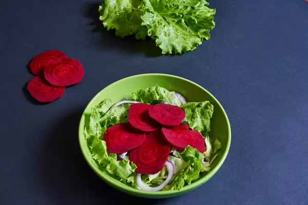 Beetroot salad with lettuce leaves on dark background