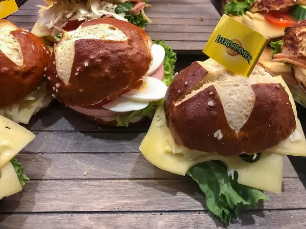Belegte Brötchen mit Leerdämmer-Käse, Ei, Wurst und Salat, angerichtet auf rustikalen Holztischen