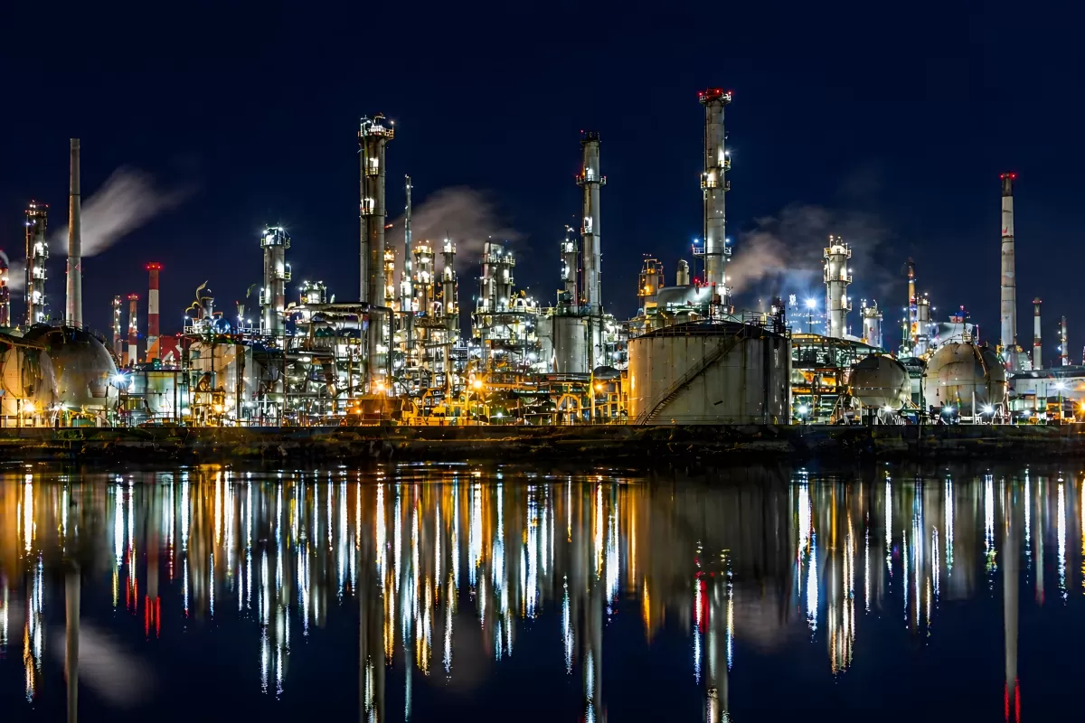 Beleuchtete Raffinerie bei Nacht mit Wasserreflexion