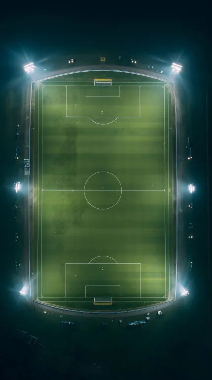 Beleuchtetes Fußballstadion bei Nacht aus der Vogelperspektive