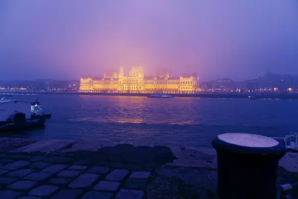 Beleuchtetes Parlamentsgebäude bei Nacht in Budapest, Ungarn, mit der Donau im Vordergrund