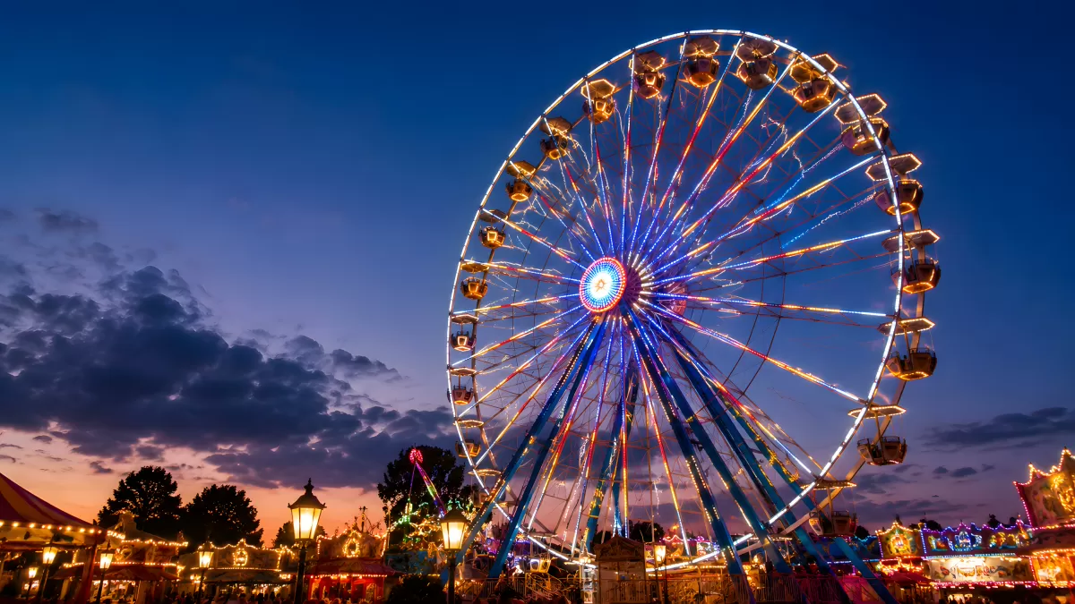 Beleuchtetes Riesenrad auf einem Jahrmarkt bei Abenddämmerung