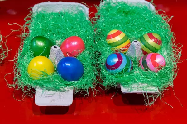Bemalte Ostereier in der Verpackung dekoriert mit Kunstgras