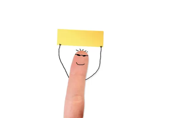 Bemalter Finger mit Gesicht hält ein leeres Blatt /Haftnotizzettel in der Hand, vor weißem Hintergrund