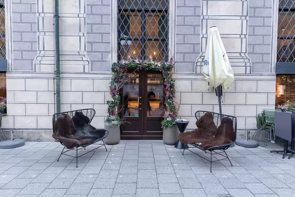 Benches with fur pads in front of restaurant entrance decorated with flowers