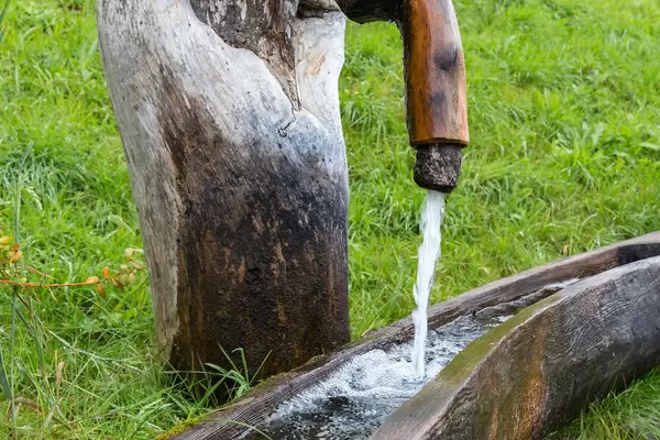 Berg-Quellwasser fließt aus einem Holzbrunnen in Alpbach in Tirol, Österreich