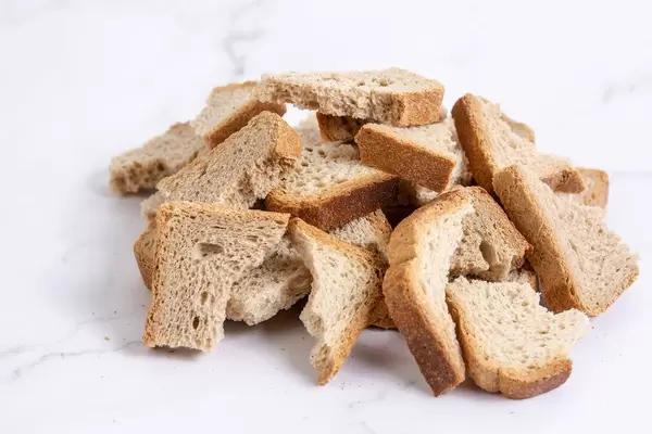 Berg von trockenem, in Stücke gebrochenem Toast auf Marmortisch