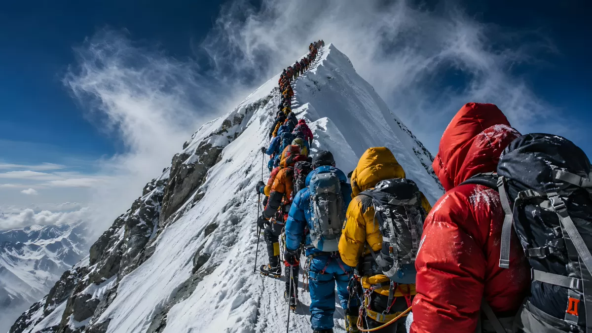 Bergsteiger in langer Schlange auf verschneitem Gipfelgrat