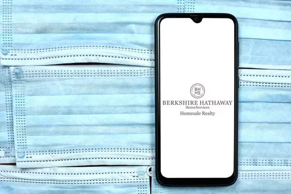Berkshire Hathaway Home Services logo on smartphone display over the face masks