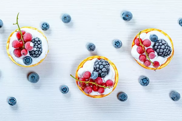 Berry cakes on a white wooden background. Top view