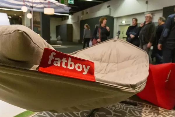 Besucher einer Messe betrachten hellbraune Hängematte aus Stoff mit integriertem Kissen