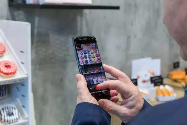 Besucher fotografiert Donuts mit seinem Smartphone bei der Anuga Lebensmittelmesse in Köln
