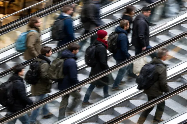 Bewegte Menschenmenge auf Rolltreppen in moderner Bahnhofshalle