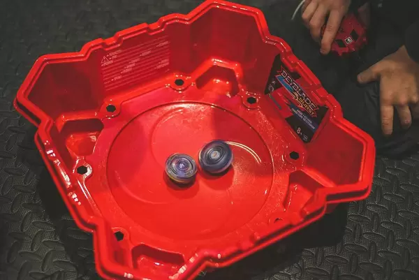 Beyblade Zirkel in roter Arena mit daneben kniendem Spieler